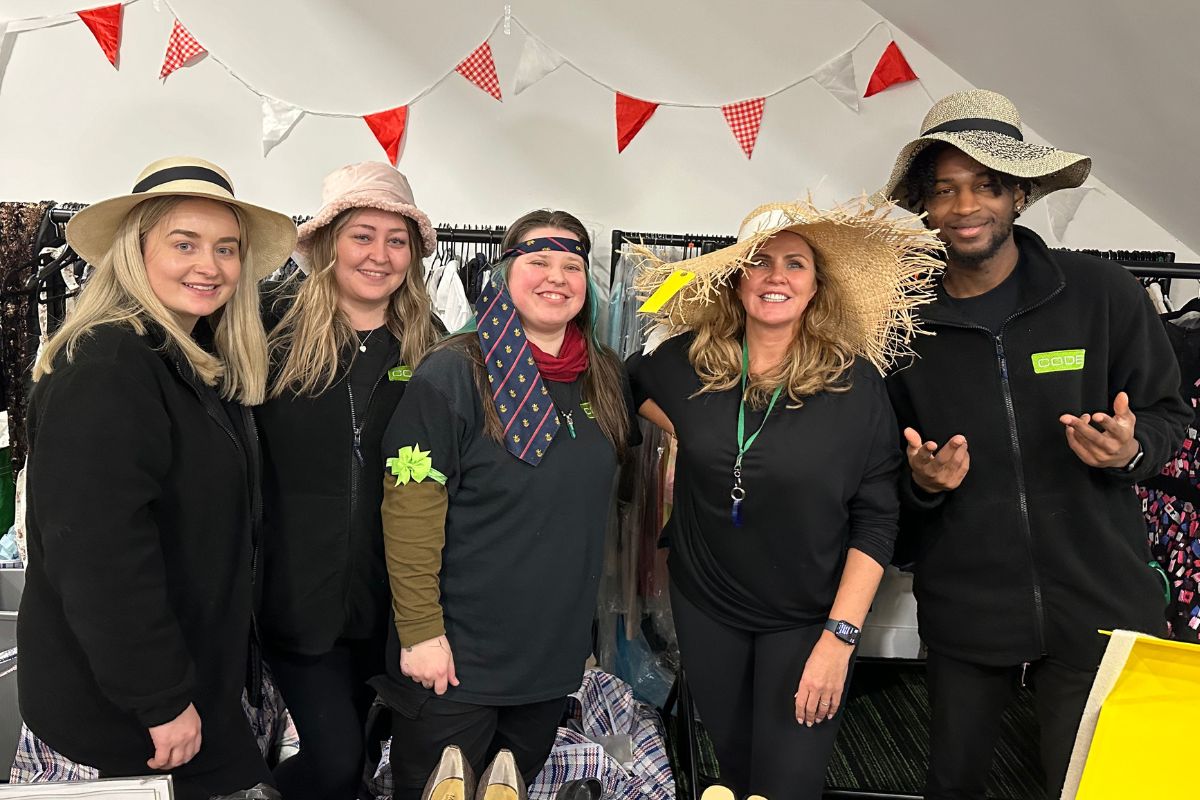 CODE Staff members wearing hats from clothes sale