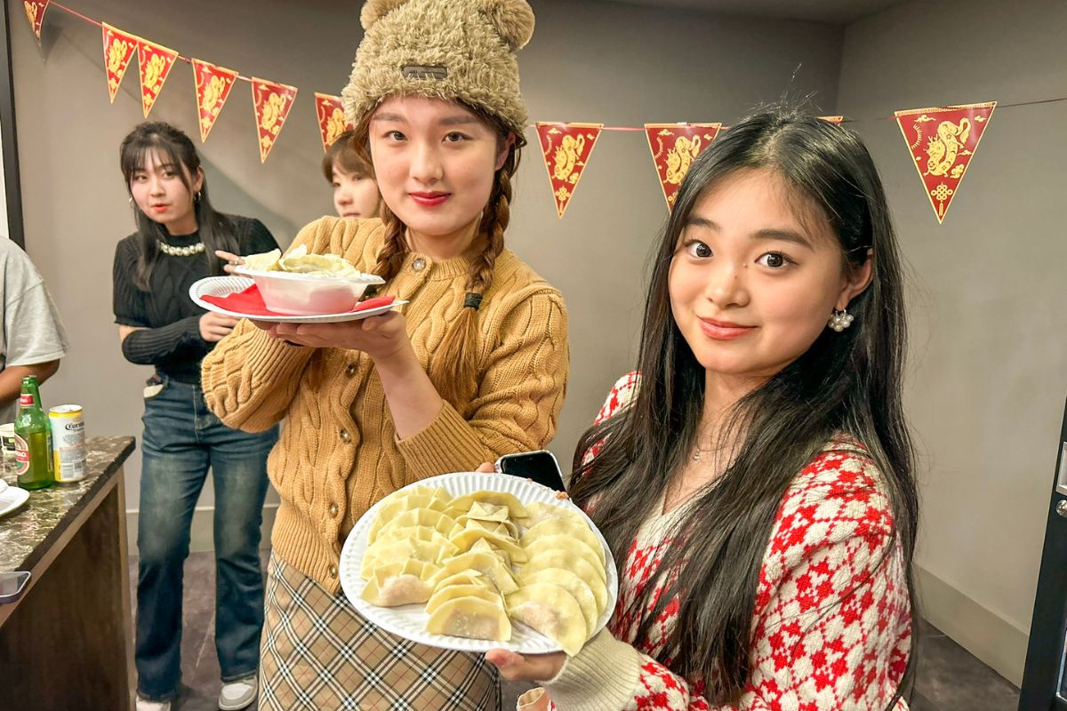Two girls holding plates of handmade dumplings