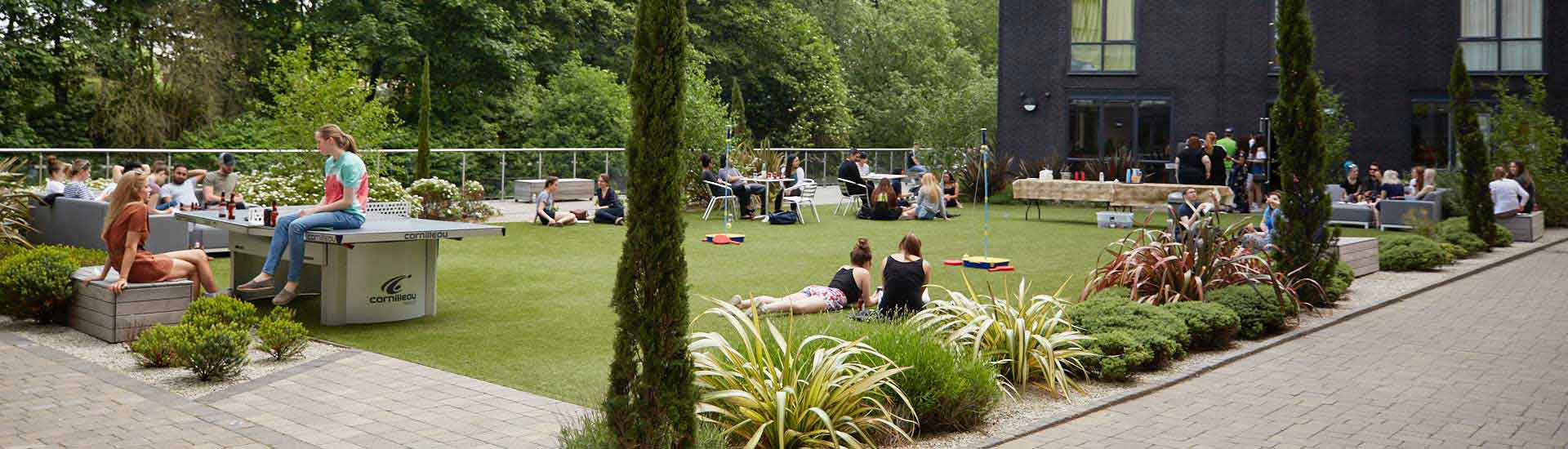 Outdoor area at CODE with students sat on the grass enjoying the sunshine
