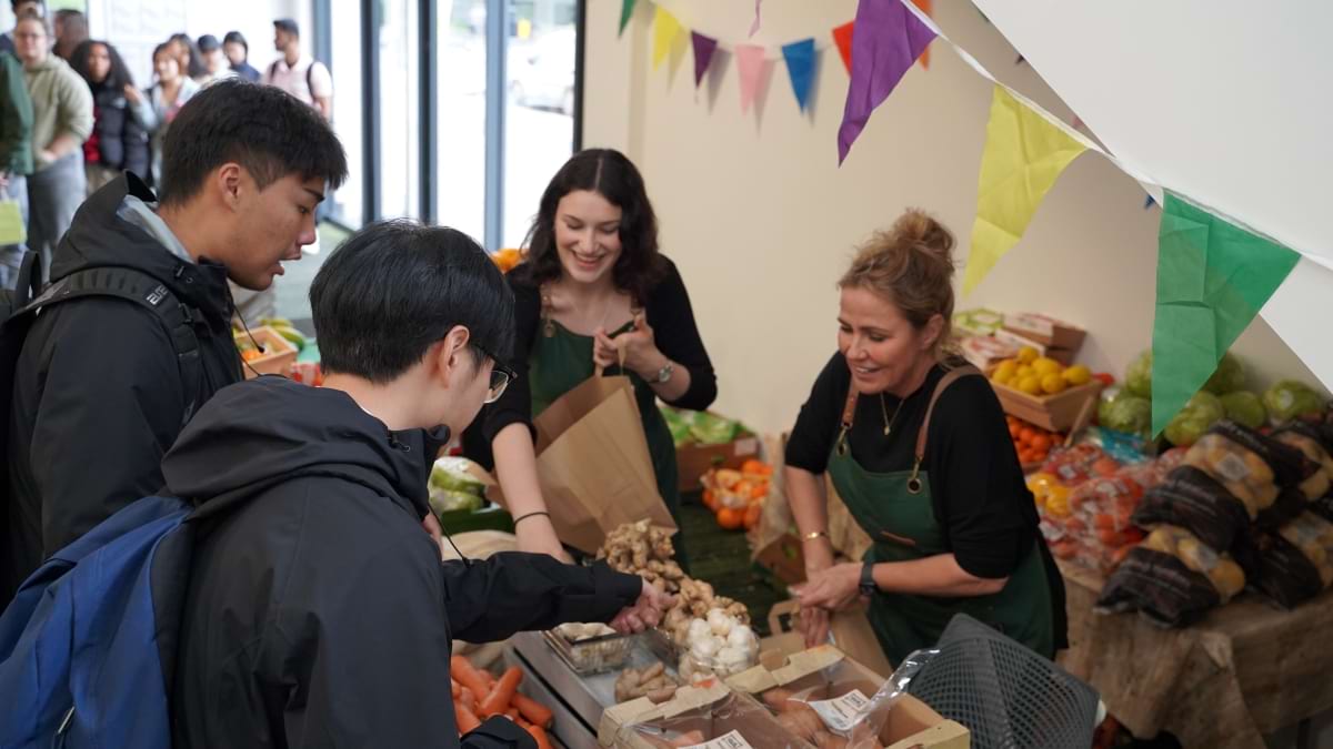 Student Pointing at a bunch of Bananas at the Fruit Stall