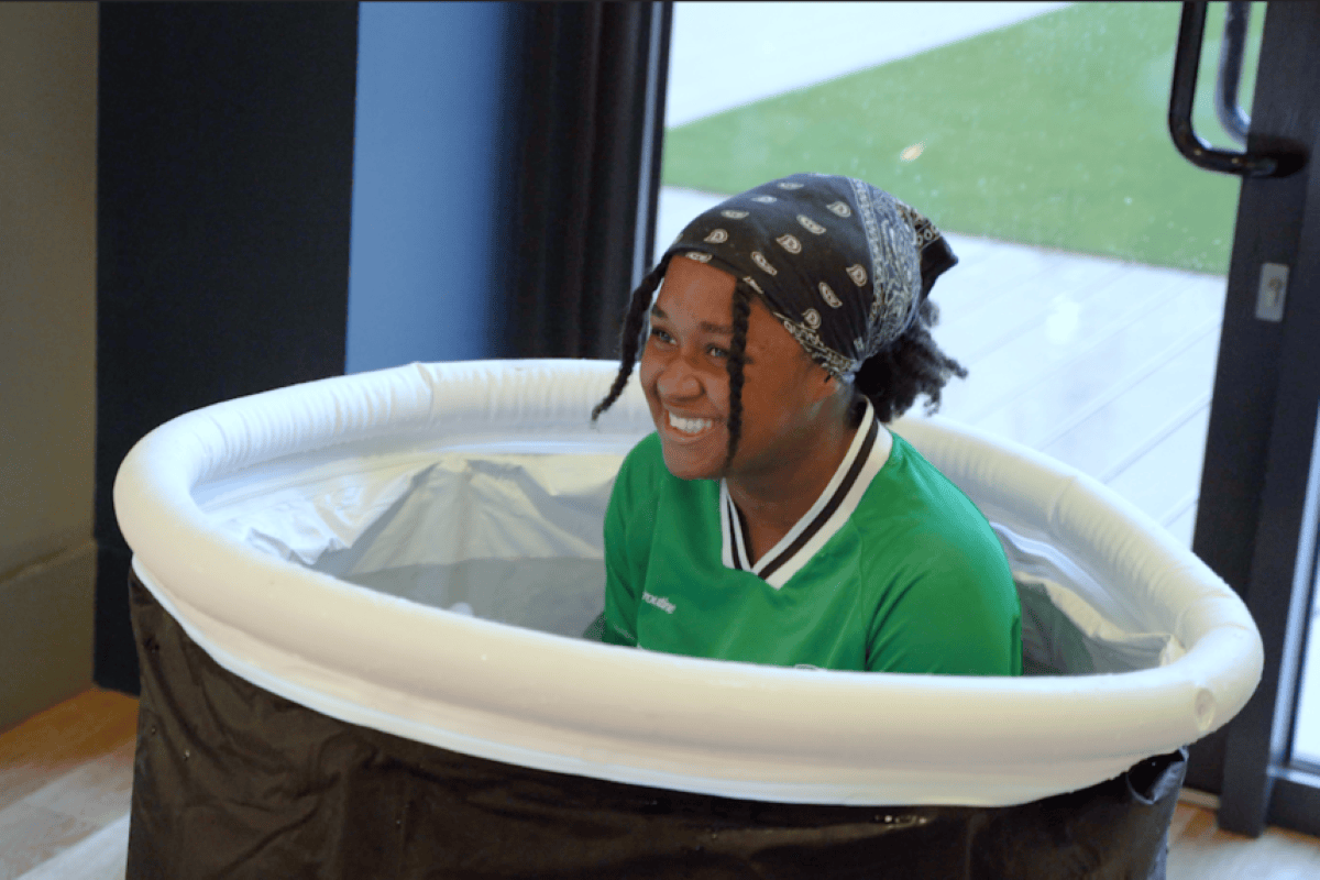 Girl laughs in shock as she sits inside an ice bath