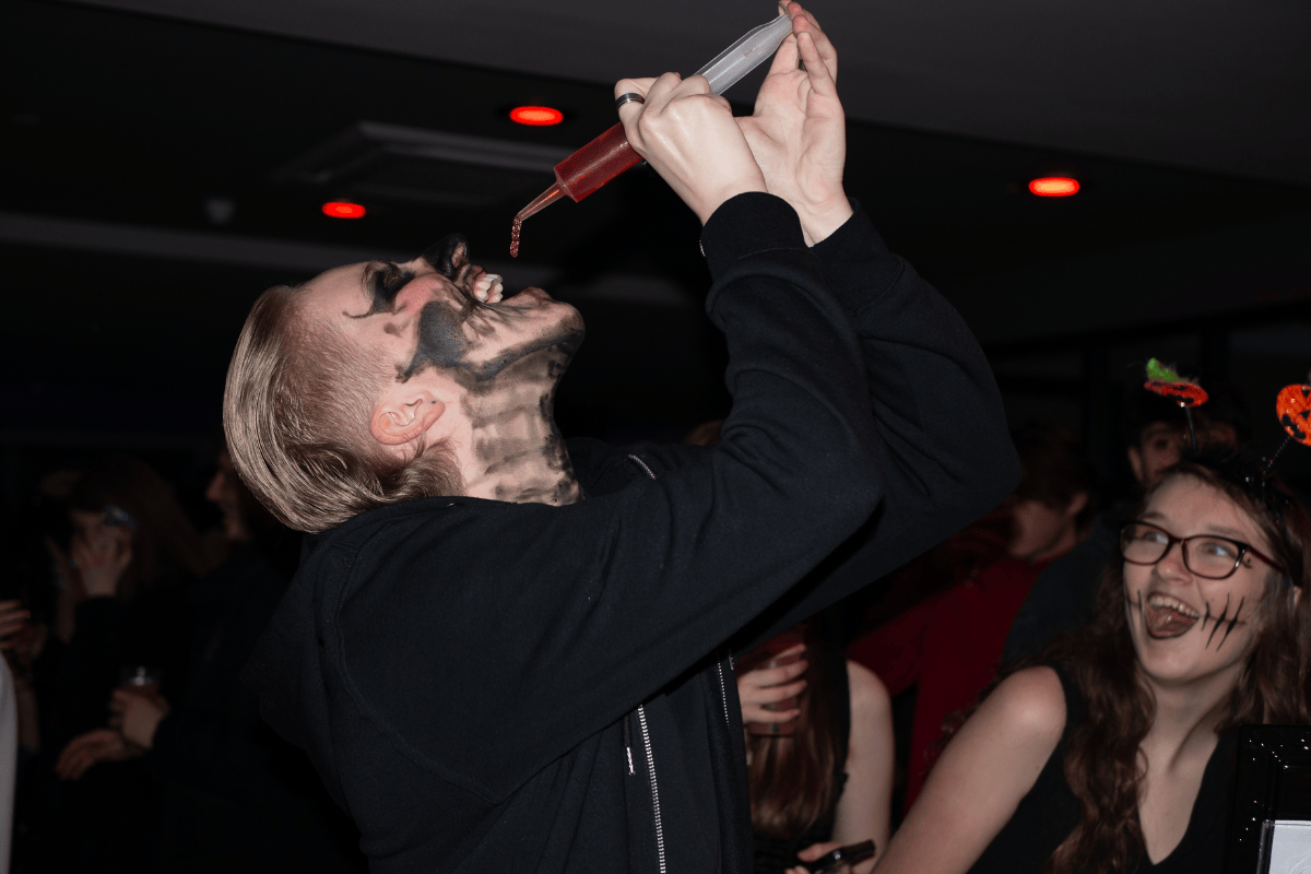 Spooky skeleton man drinking jello shots from a syringe prop