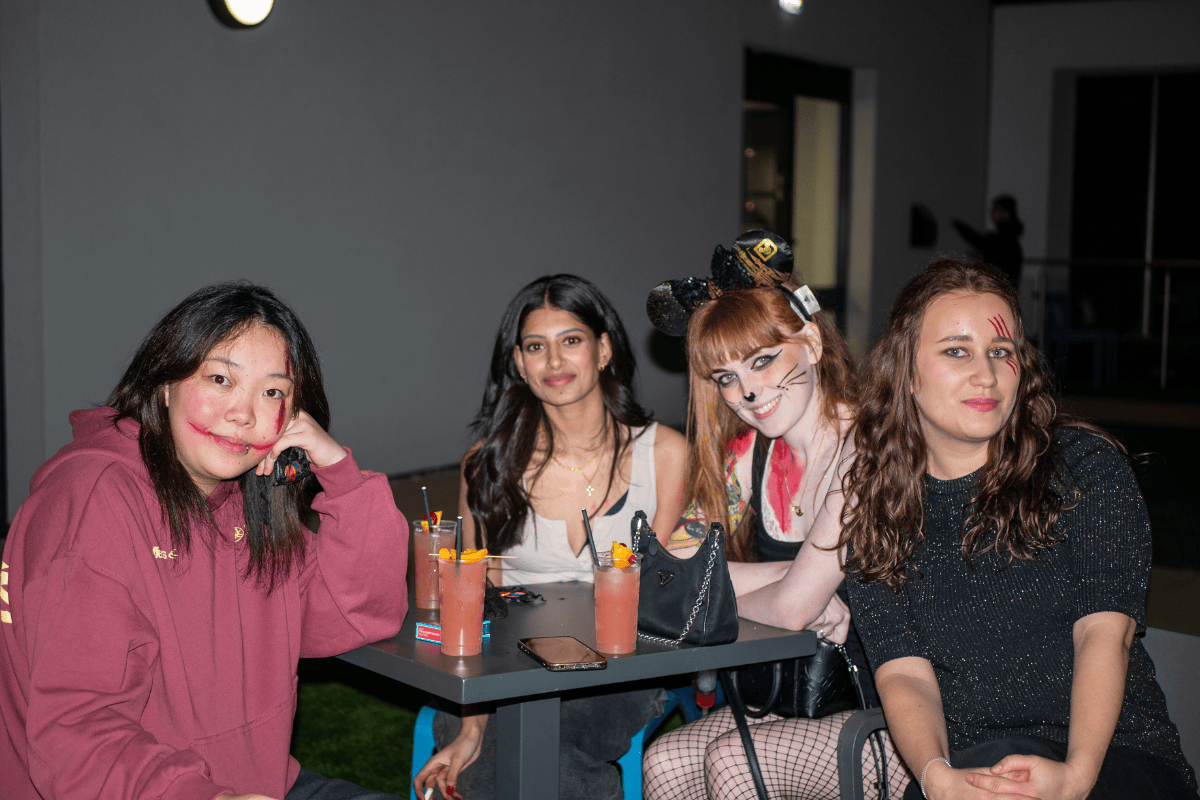 Students sit and smile for the Halloween party with cocktails