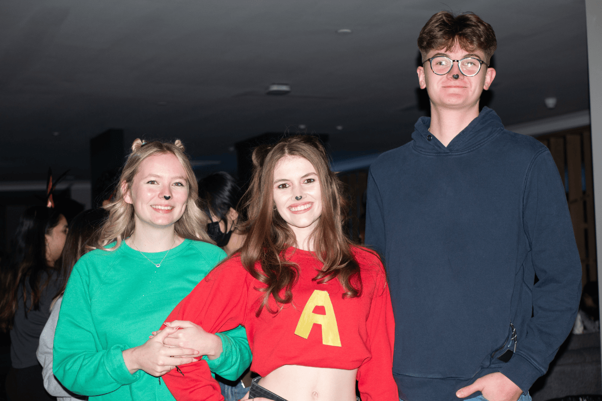 Three friends dressed as Alvin and The Chipmunks pose linking arms