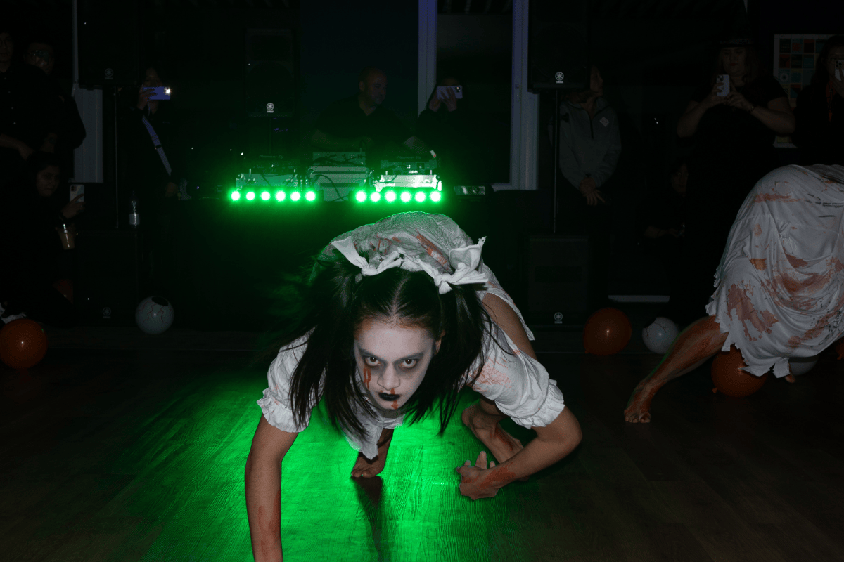 Zombie dancer looks menacingly into the camera in green light