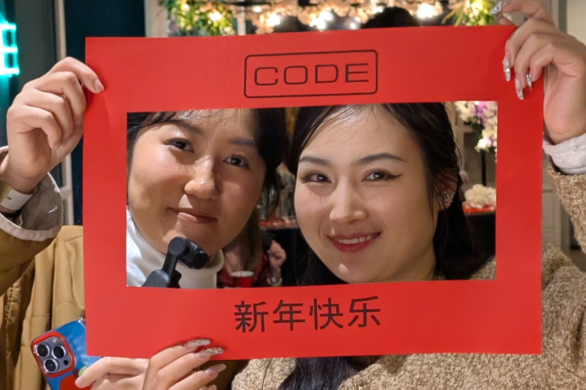 Two friends smile through a red photo frame