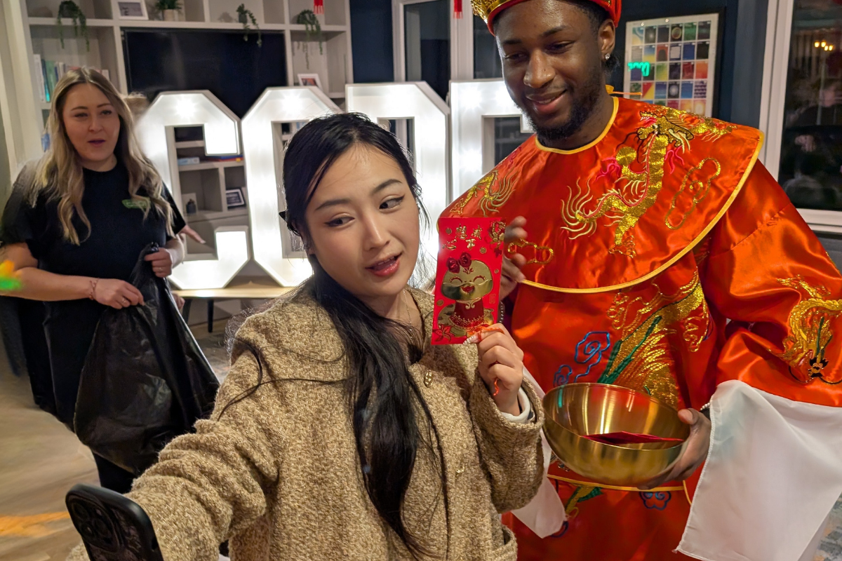 Student snaps a selfie with a man in an elegant red gown