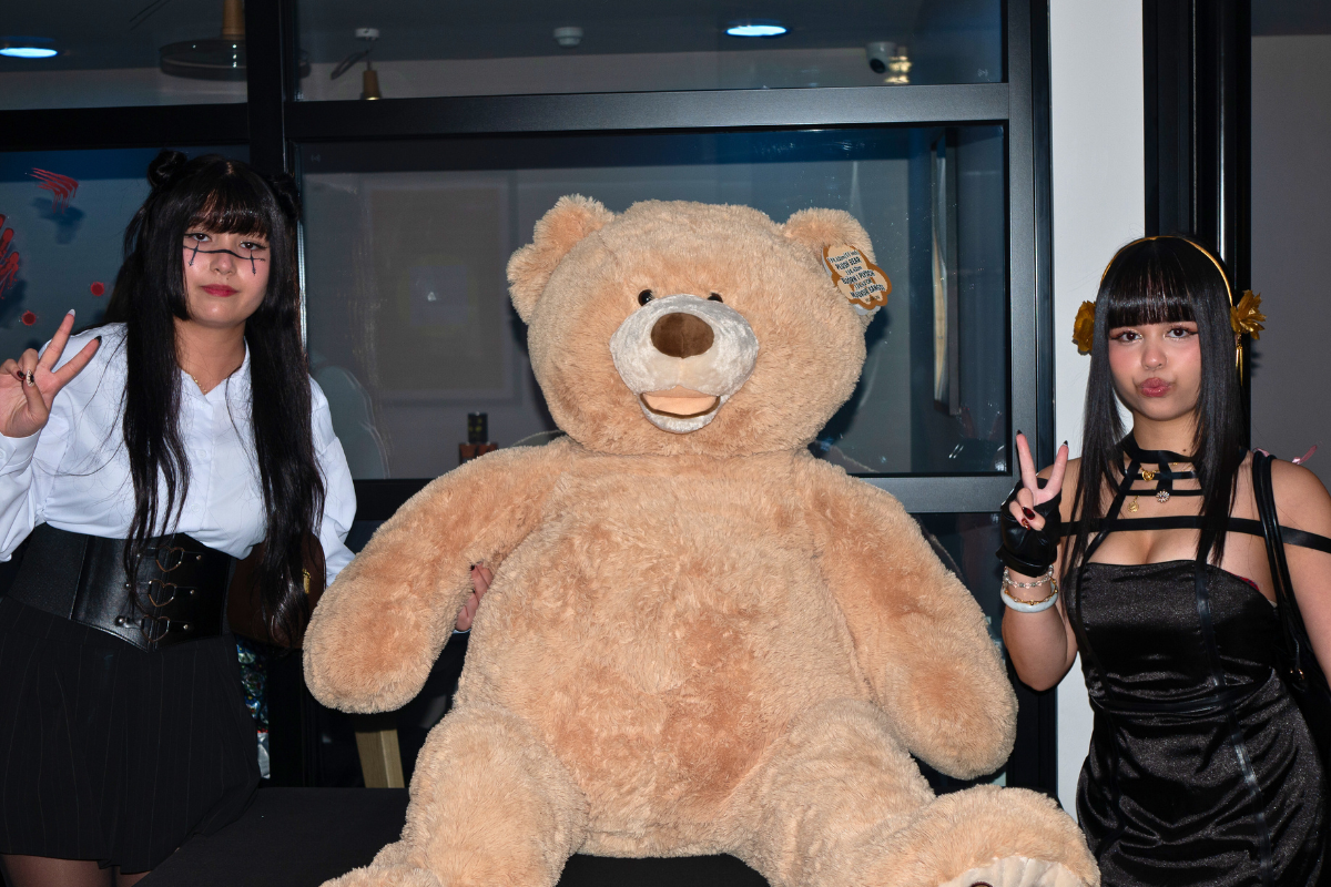 Two tenants posing for the camera next to a huge teddy bear