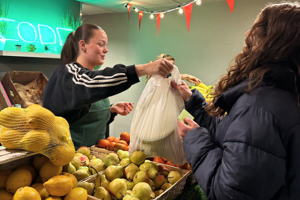 A CODE team member handing a bag of fruit and veg to a CODE tenant