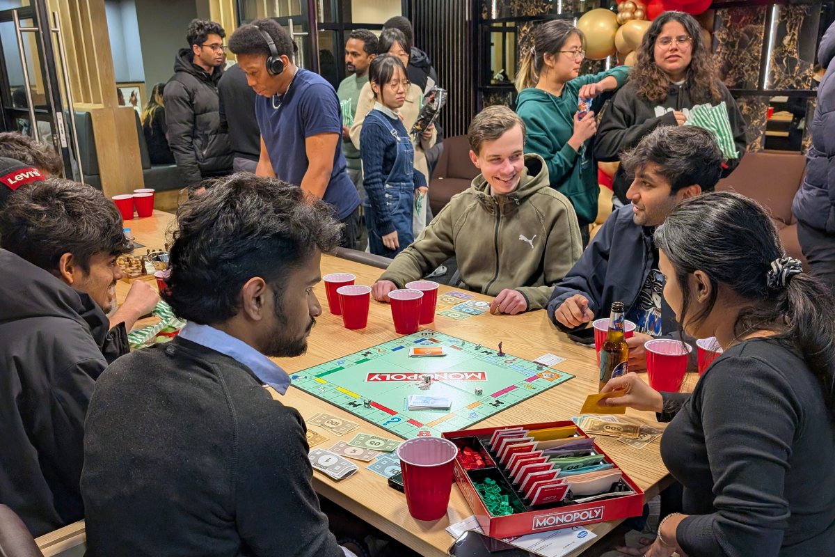 A group of friends playing monopoly at the games night in Coventry