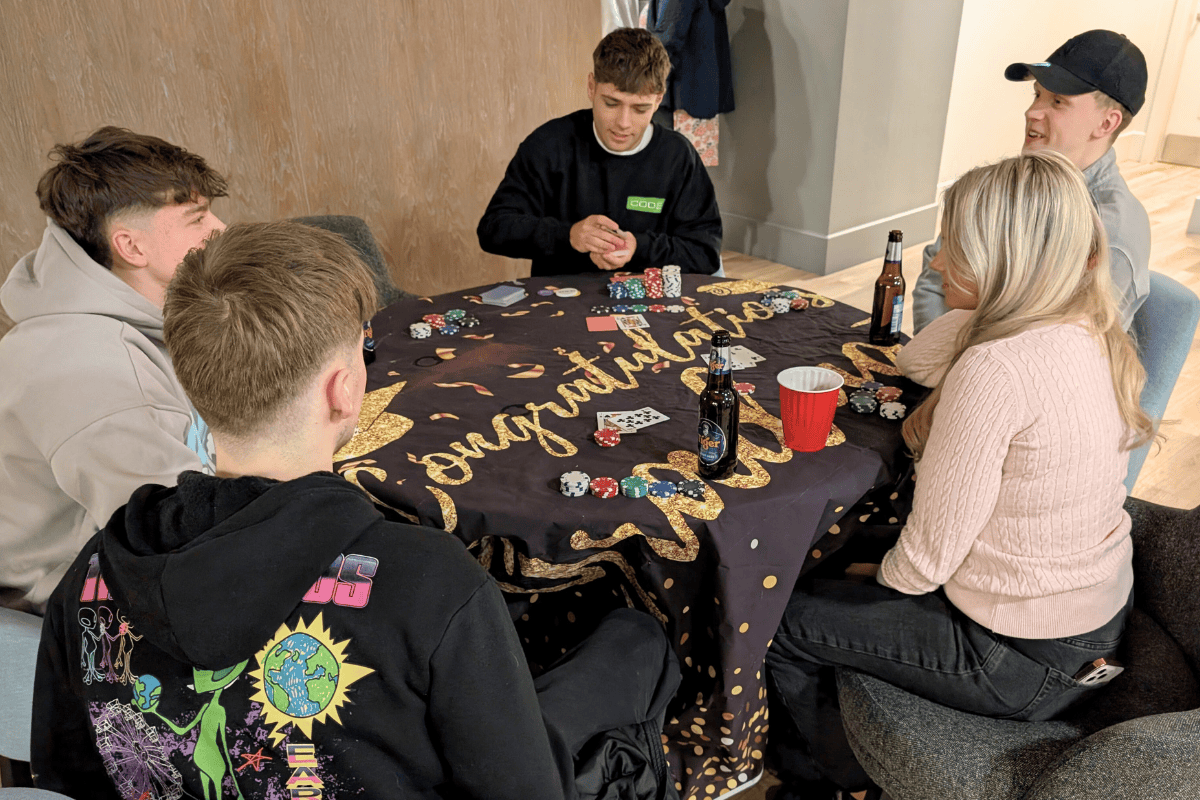 Four students sitting down at our poker table at the games night