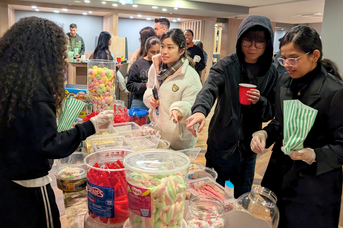 Students lining up to get sweets, some of the tenants are pointing at the sweets to let the CODE team know what they want