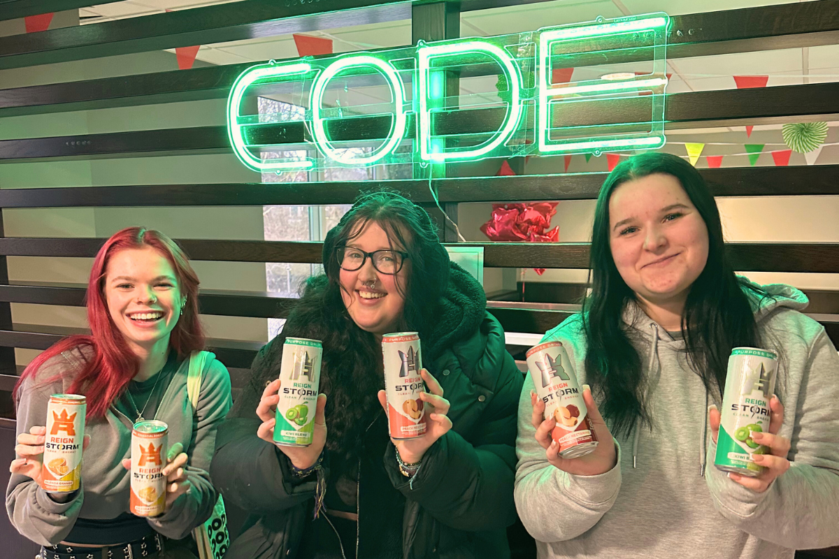 Three friends posing with drinks in their hands in front of the camera all smiling at the CODE energy drink event