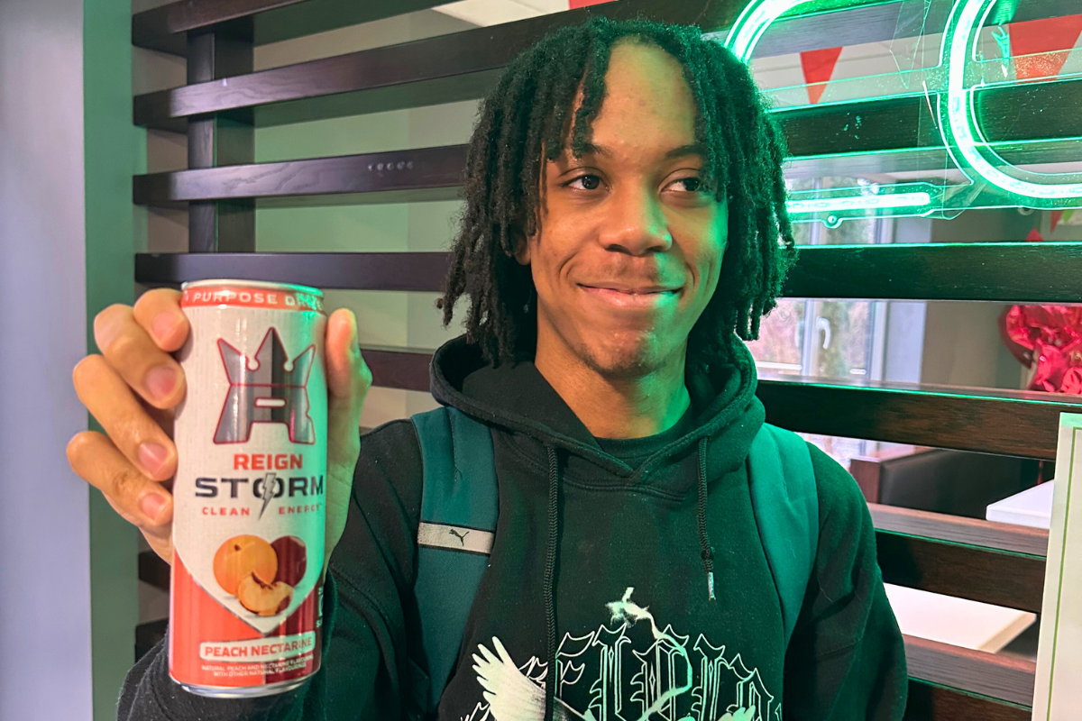 A student holding up a drink in front of the camera