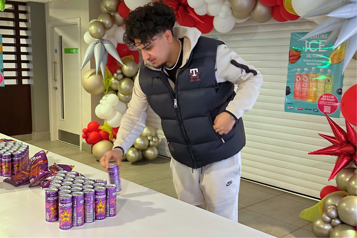 A student reaching over the table to grab an energy drink at the CODE Energy drink event