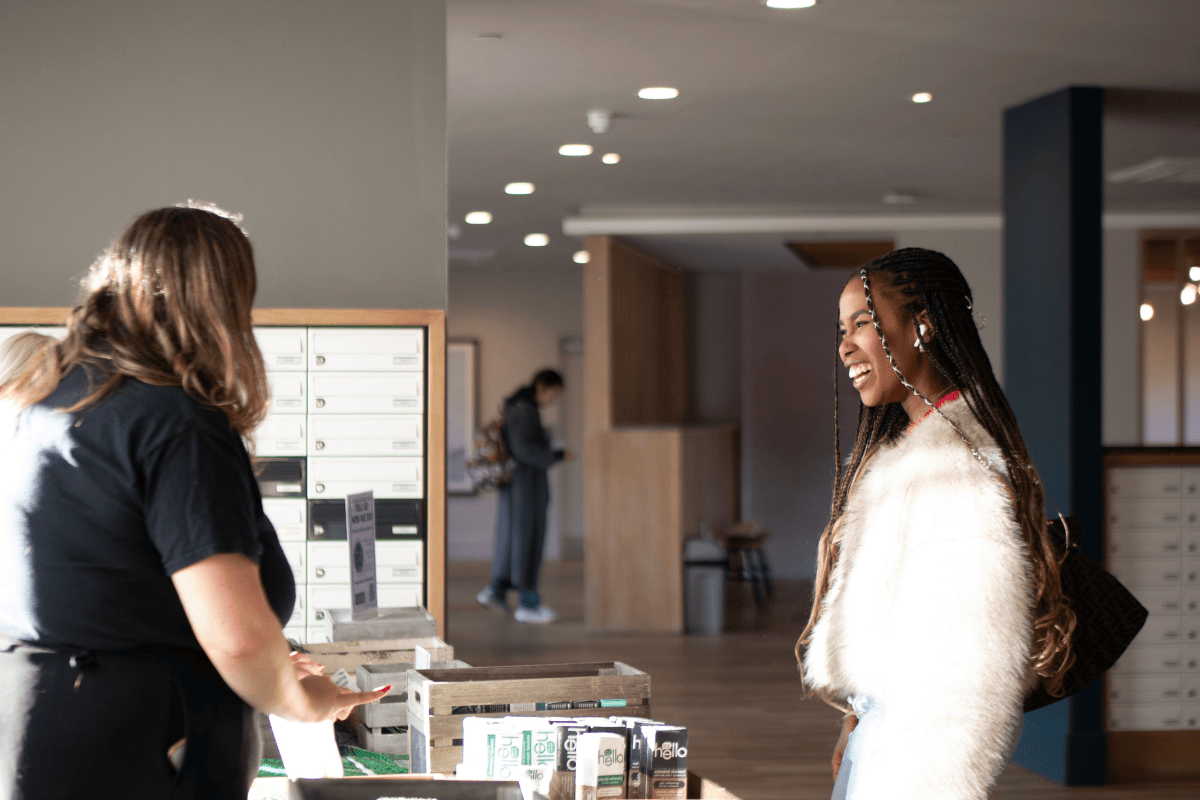 Student smiles whilst greeting staff at pamper giveaway table