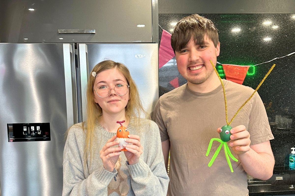 Two code students holding up their decorated eggs for the egg competition