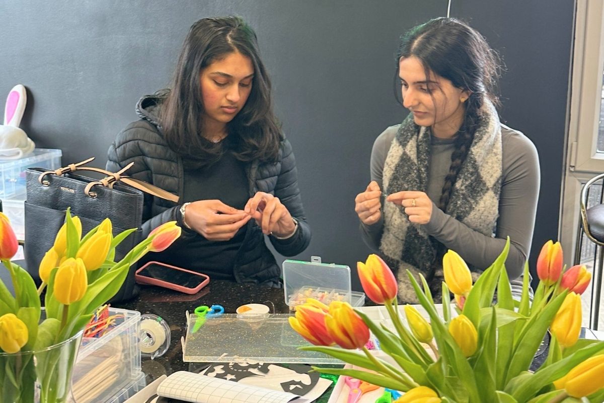 two girls making bracelets at the code easter crafting event