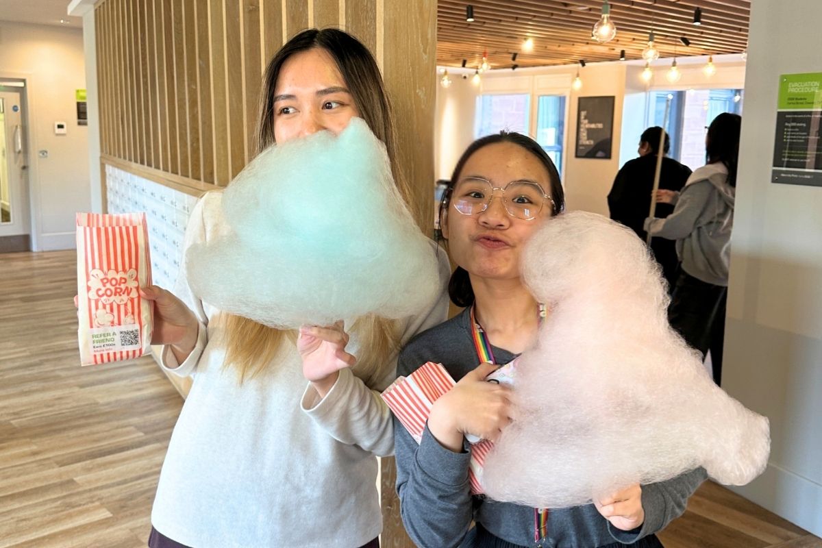Two friends holding some popcorn and candy floss at the CODE event