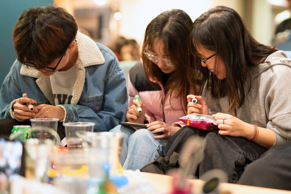 Three friends looking at their bingo cards at the CODE bingo event