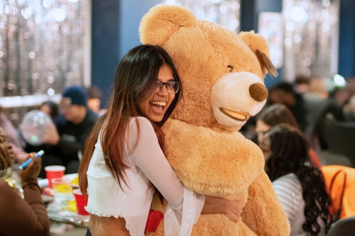 A girl hugging a massive teddy that she won at the code bingo event