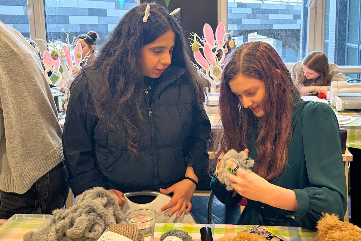 two students making pom poms together