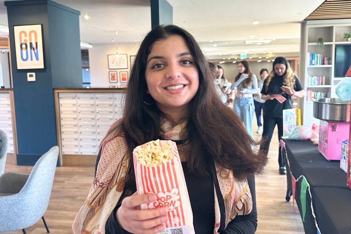 A CODE tenant smiling while holding her popcorn