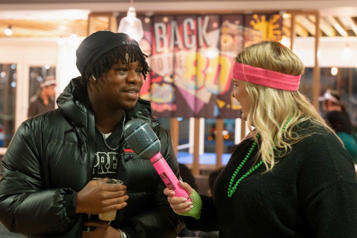 A girl interviewing a boy using a massive blow up mic