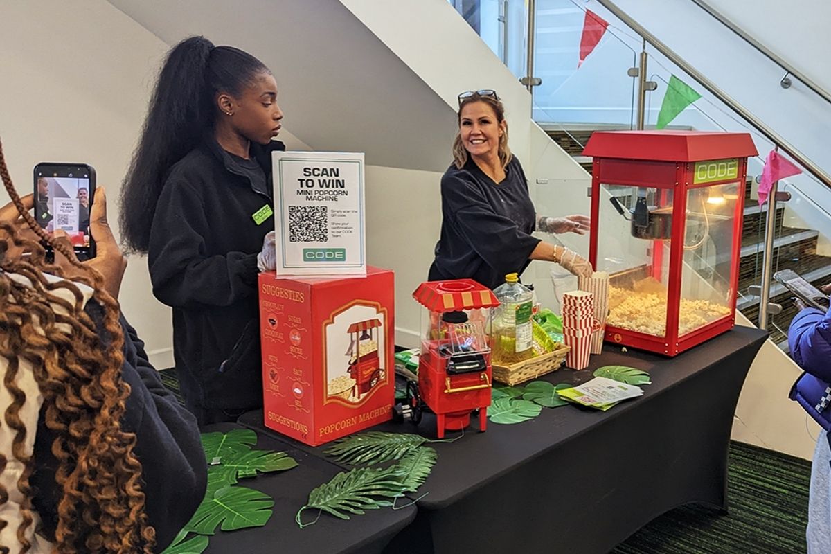 student taking photo on mobile of smiling staff at popcorn giveaway event