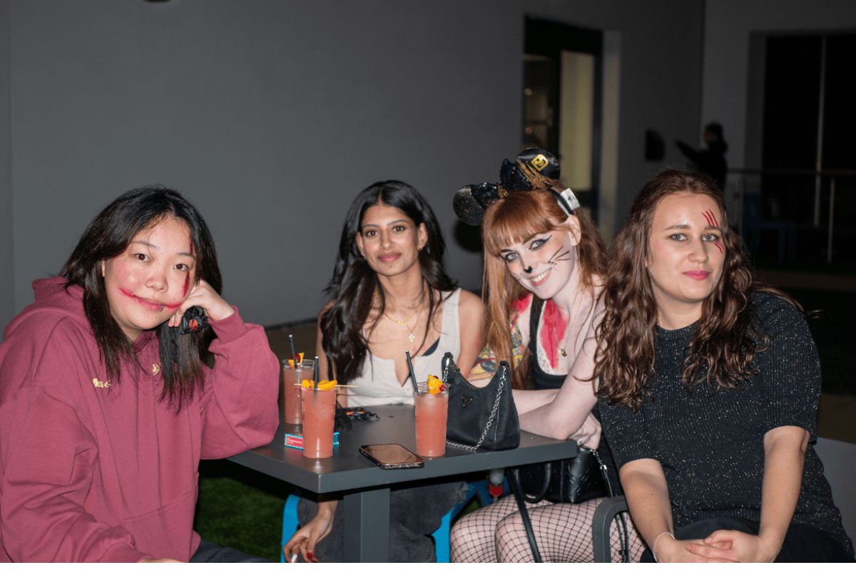 Students sit and smile for the Halloween party with cocktails