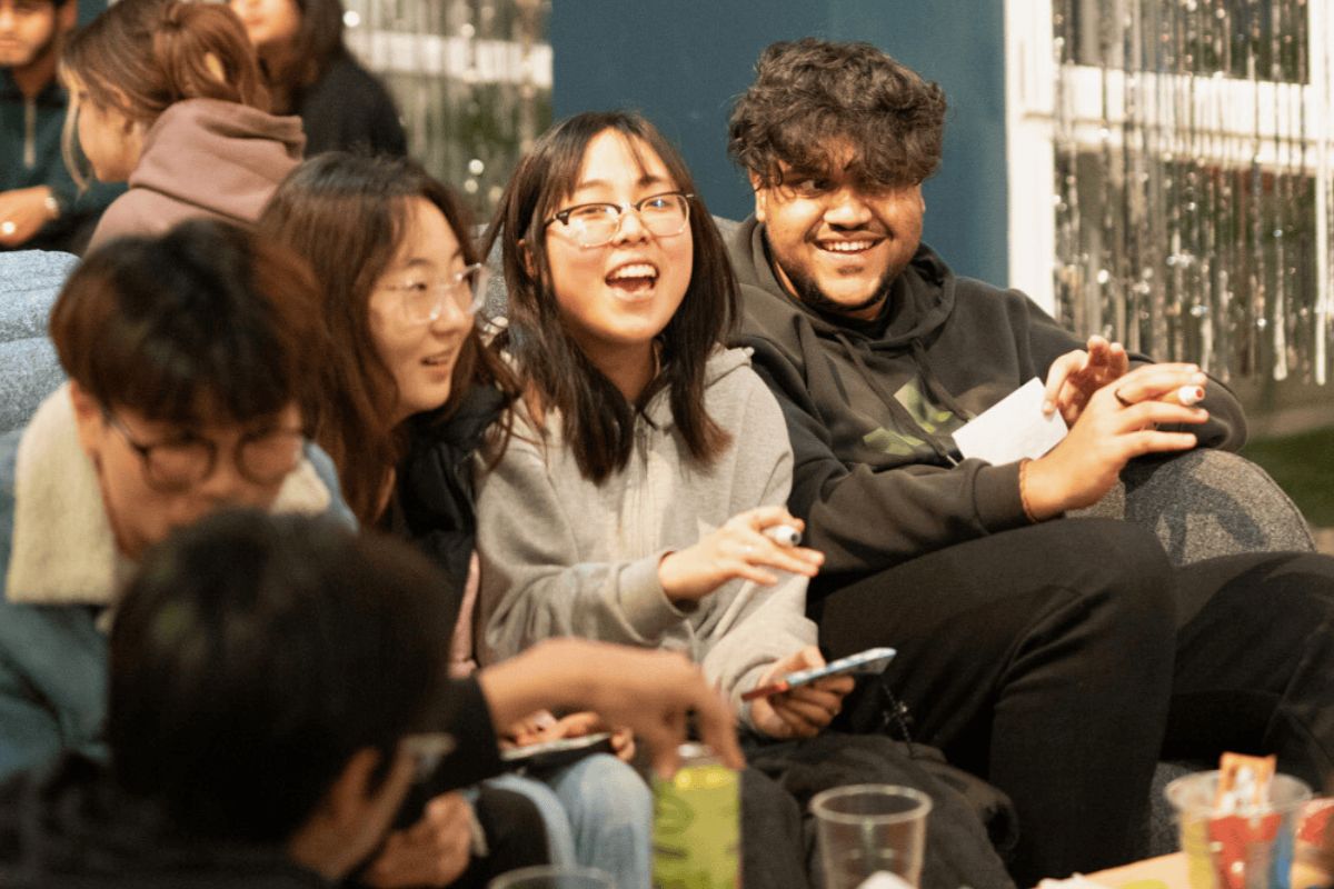 CODE students sitting in a sofa playing bingo