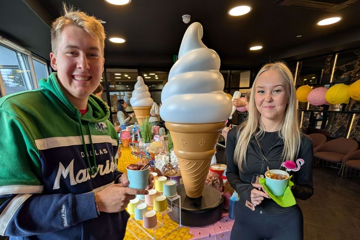 Two students holding their ice cream cups full of ice cream looking all happy