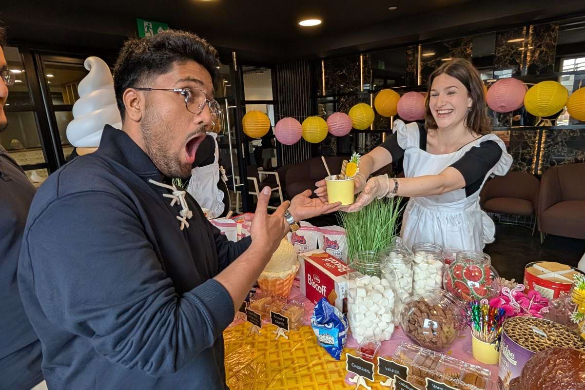 A excited student looking super happy being handed the ice cream from the CODE team member