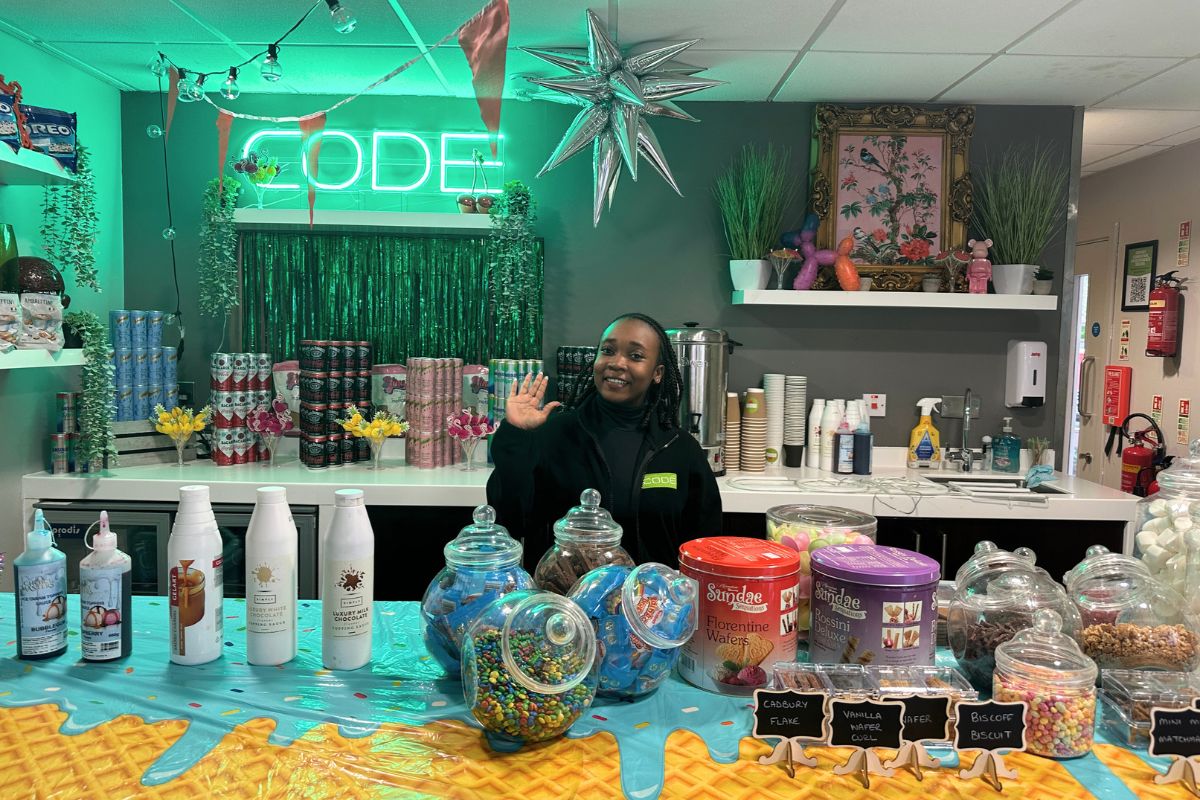 A CODE team member waving while standing behind the bar at the End of Year Ice Cream and Cocktail party