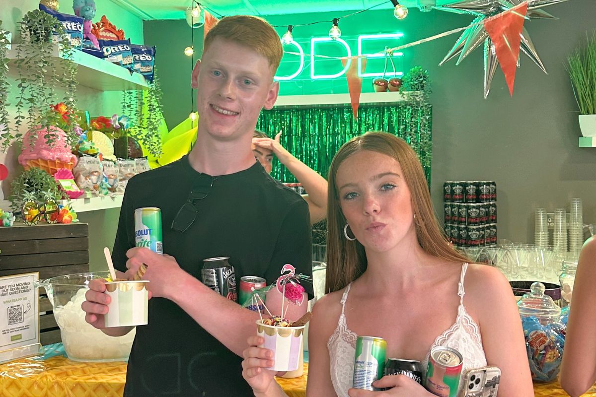 Two students holding their drinks and Ice Creams in front of the ice cream bar area