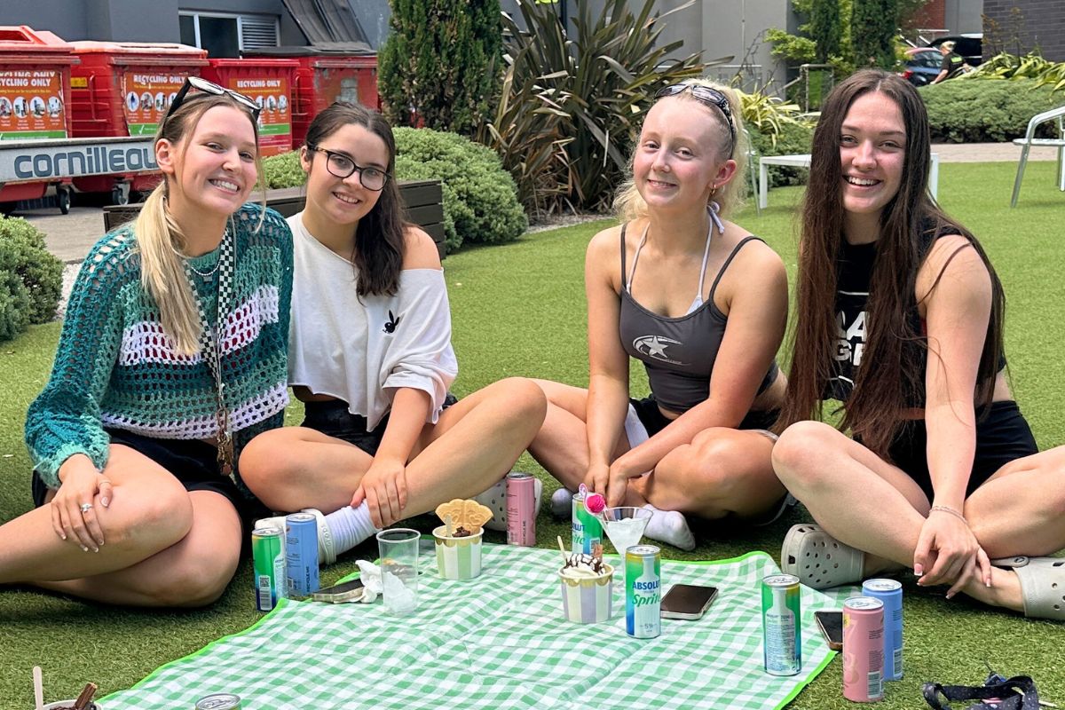 Students sitting on a picnic blanket together enjoying their cocktails and ice cream