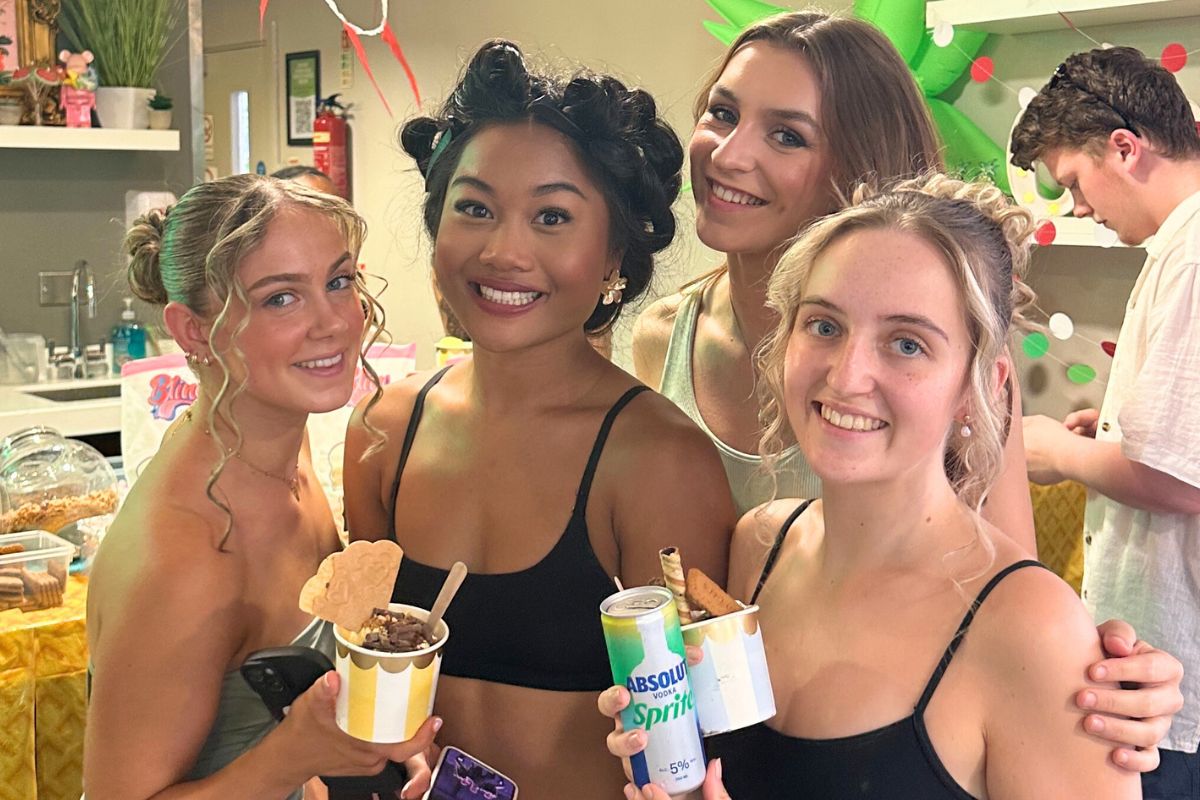 Four girls smiling together in the que to get their ice creams and cocktails