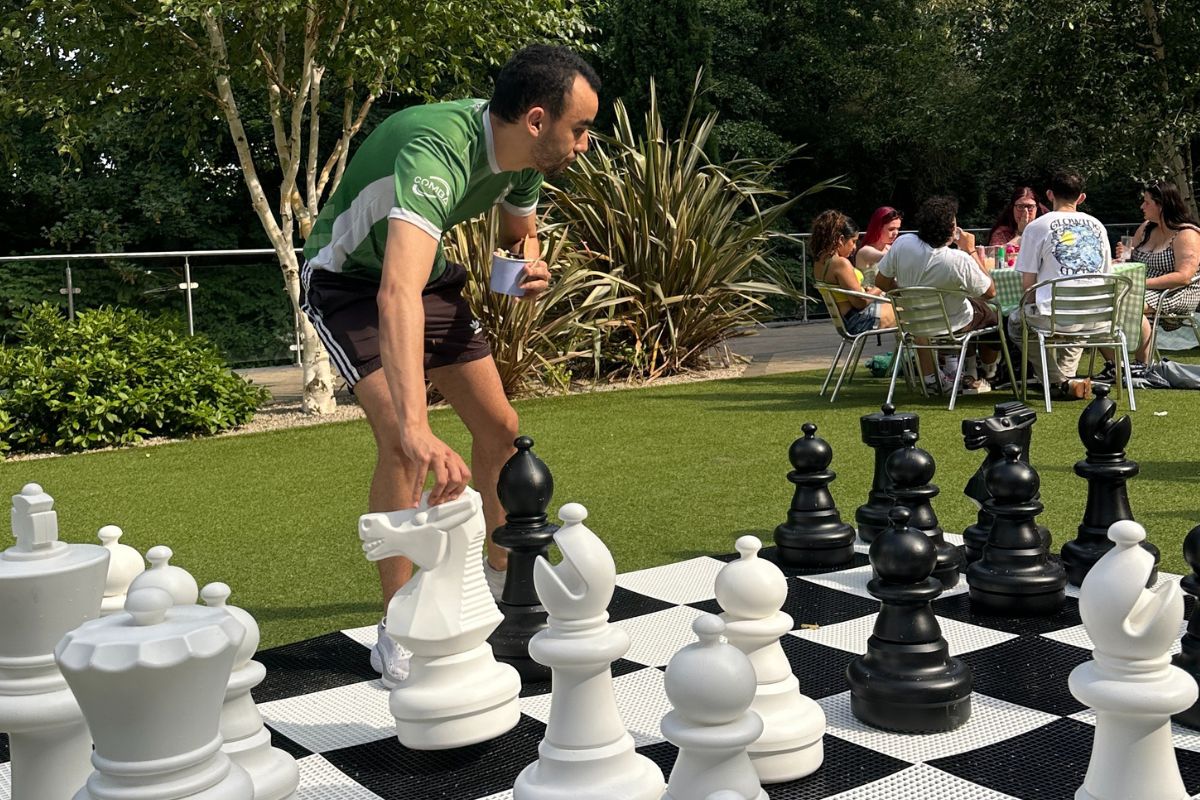 A tenant holding his ice cream while playing chess at the CODE event