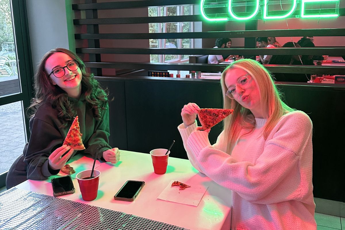 two girls with pizza in their hands smiling