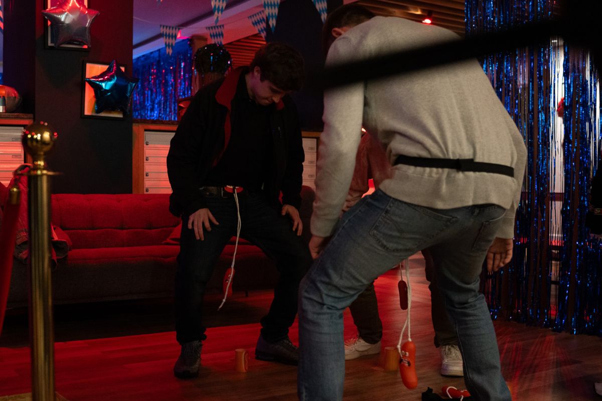 Three students compete in a party game with sausage on a string