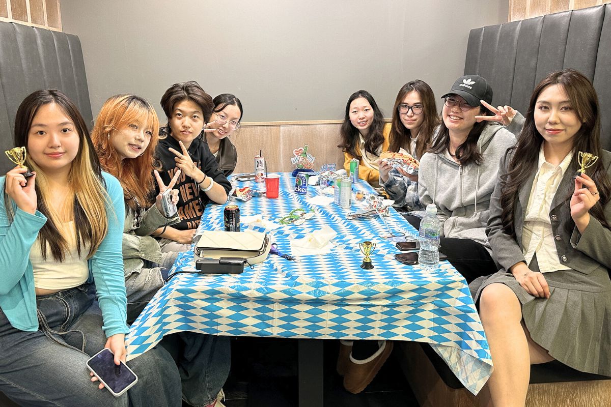 Eight friends proudly show their trophy prizes and flash peace signs