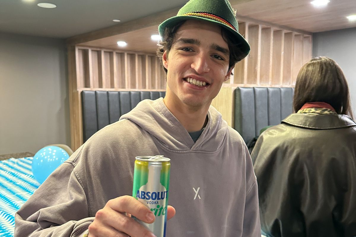 Student smiling holds up a drink