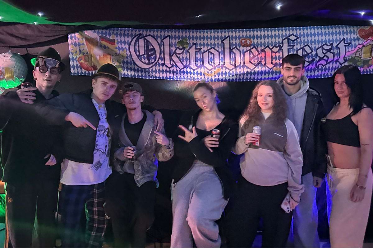 CODE student tenants standing in front of the Oktoberfest banner