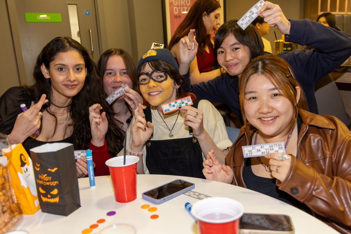 A group of CODE students holding up their bingo cards