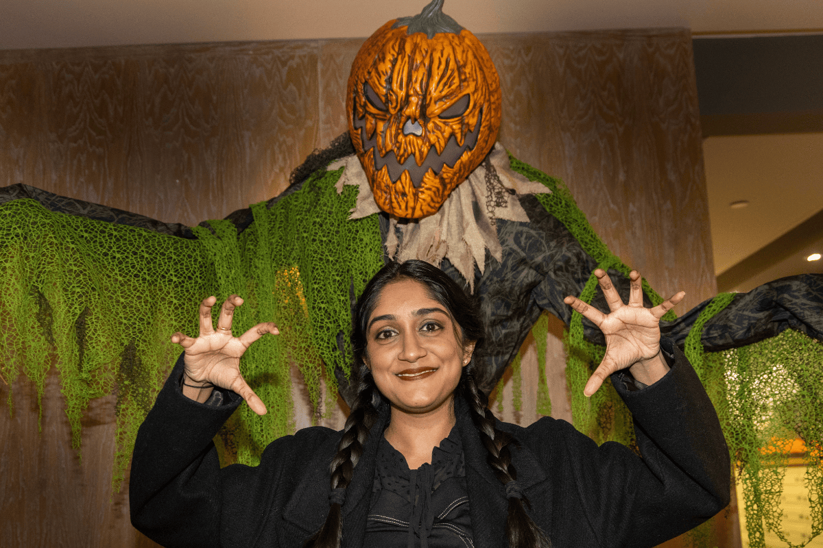 A CODE tenant posing in front of the pumpkin man decoration