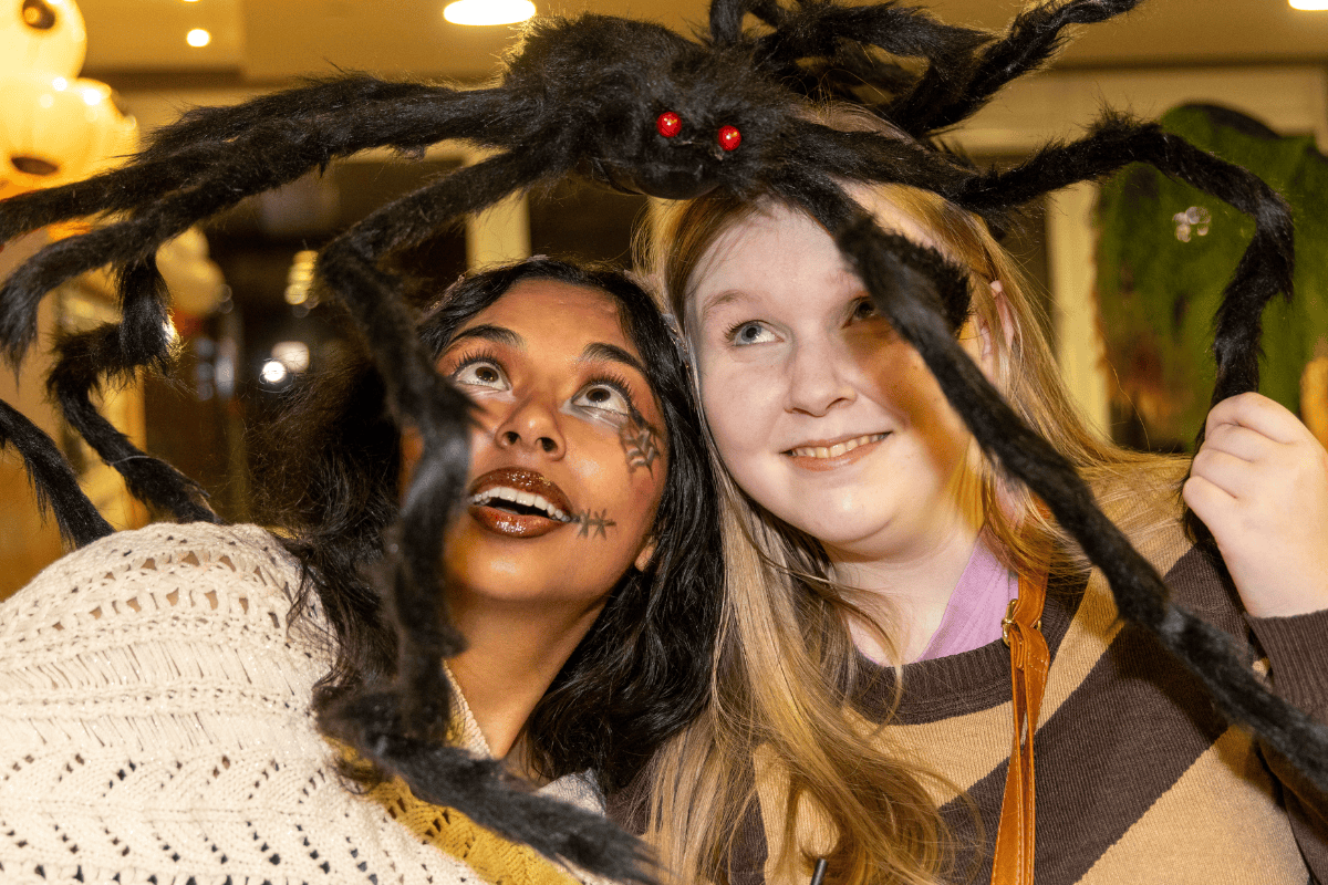 Two CODE tenants holding the decoration spider over their head