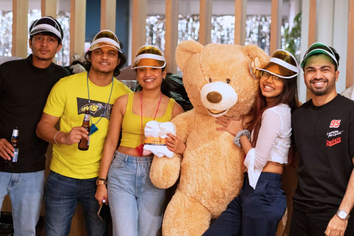5 friends smiling and posing with a large teddy bear