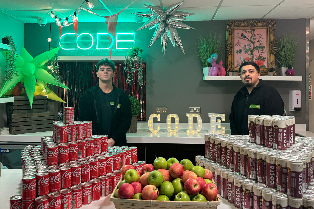 2 code staff posing for photo behind bar