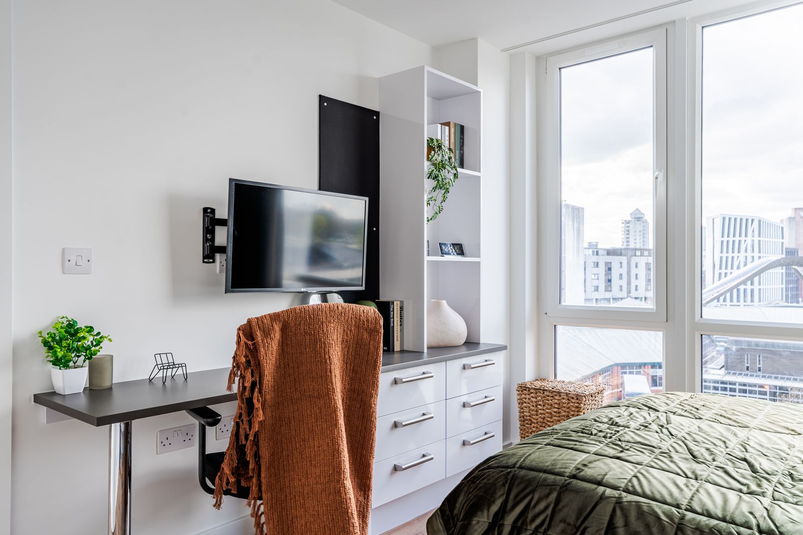 Study area by a bright window with desk, shelves and chair