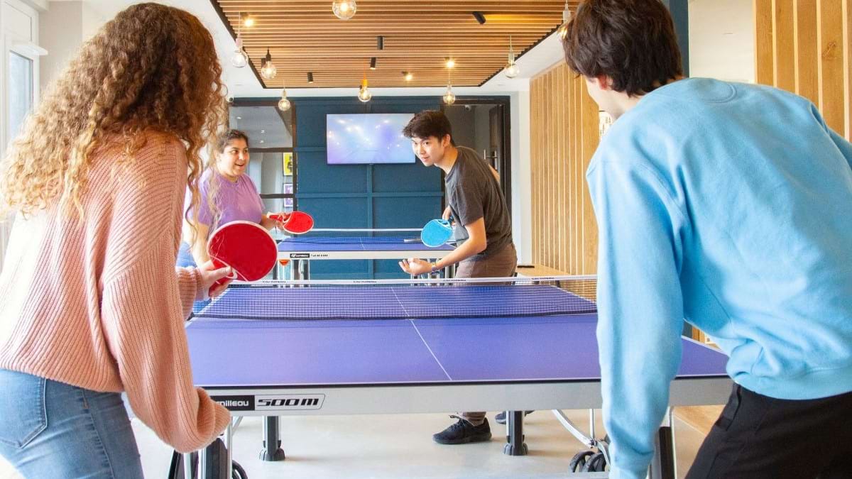 Students playing table tennis in the communal room at CODE Student Accommodation Coventry